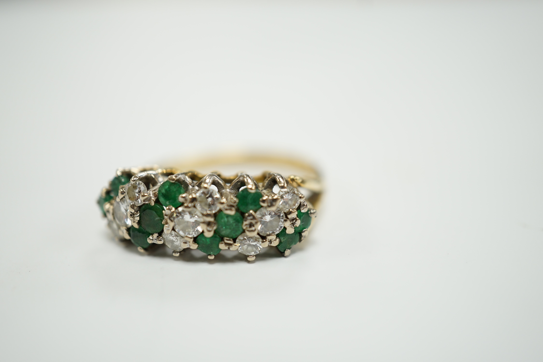 A modern 18ct, emerald and diamond set cluster half hoop ring, size O, gross weight 4.9 grams.